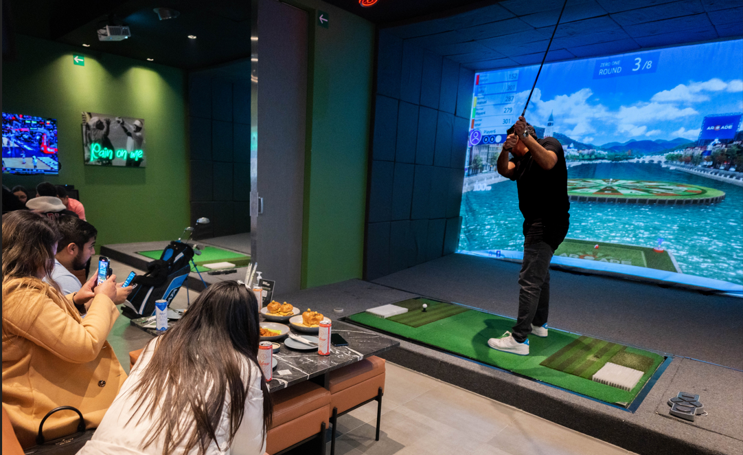 Grupo de personas disfrutando de un emocionante juego de golf en los simuladores Golfzon de Golf Station.